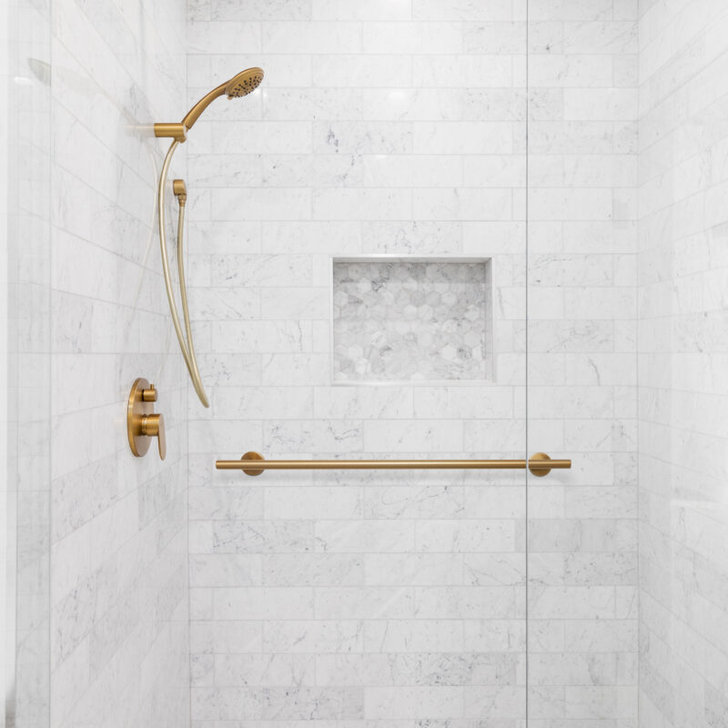 A luxury shower with a gold faucet and shower head, marble subwa