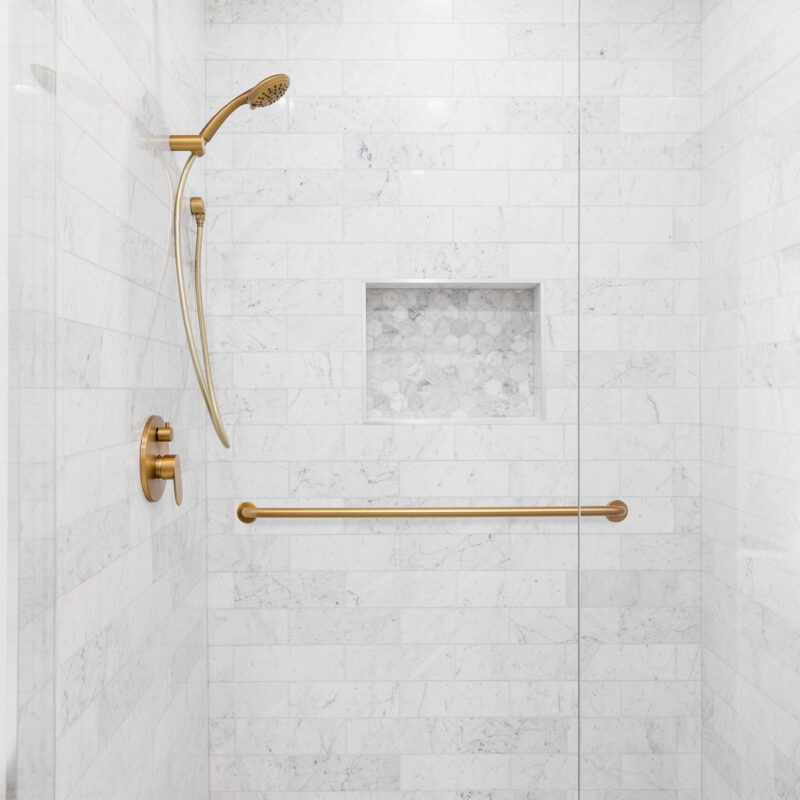 A luxury shower with a gold faucet and shower head, marble subwa