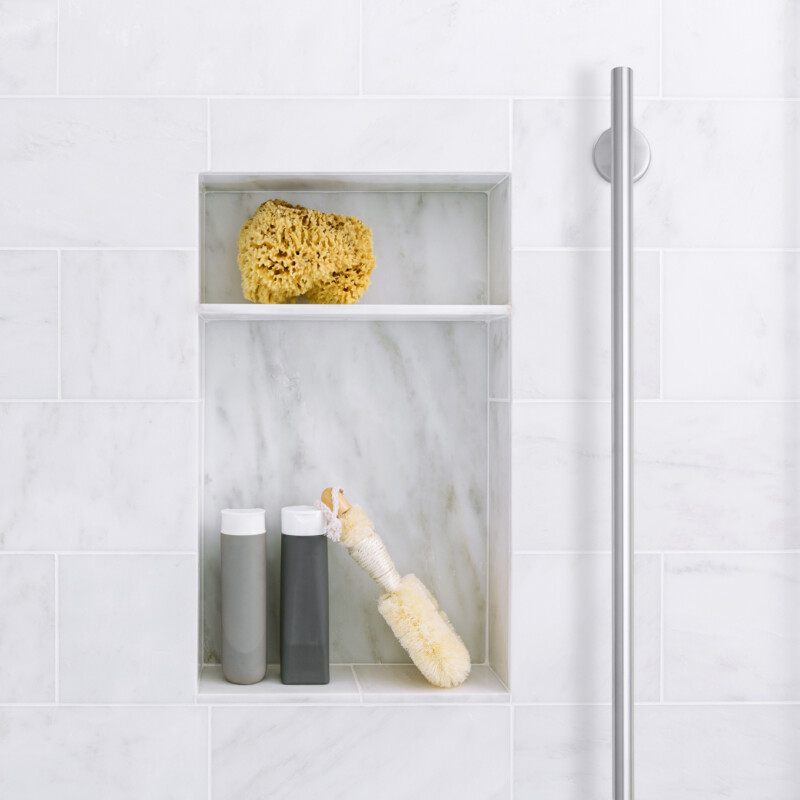 Bathroom shower interior with gray marble tile and shelves with