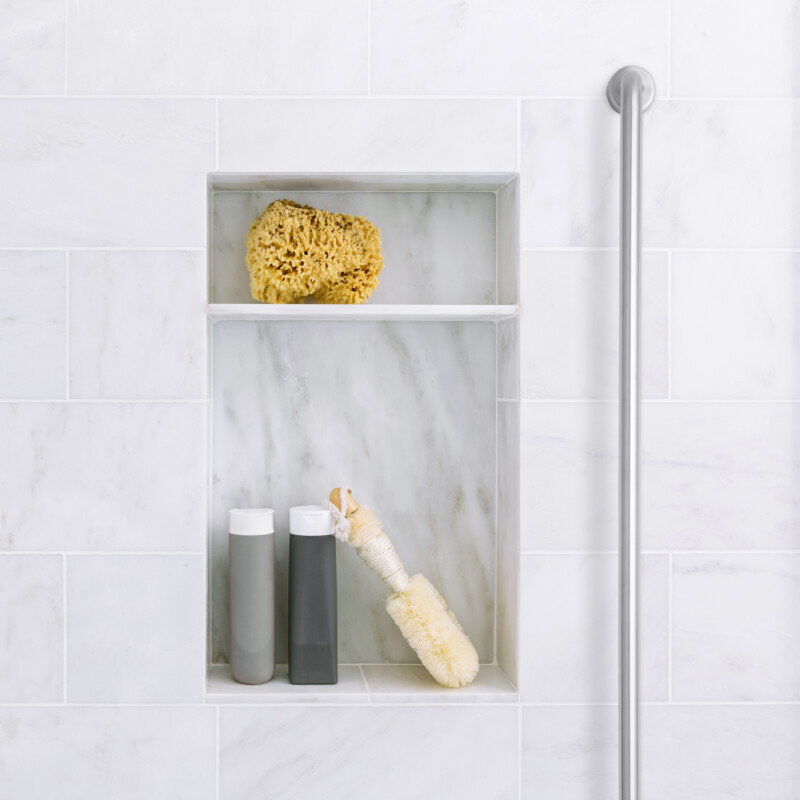 Bathroom shower interior with gray marble tile and shelves with