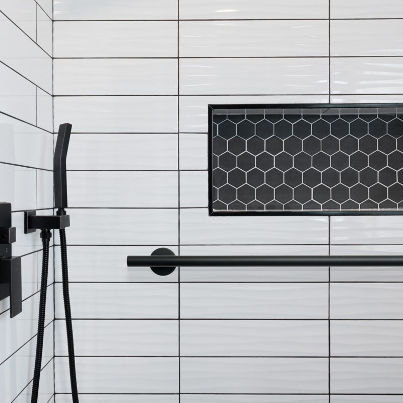 Detail of walk-in shower white subway tile, black hexagon tile i