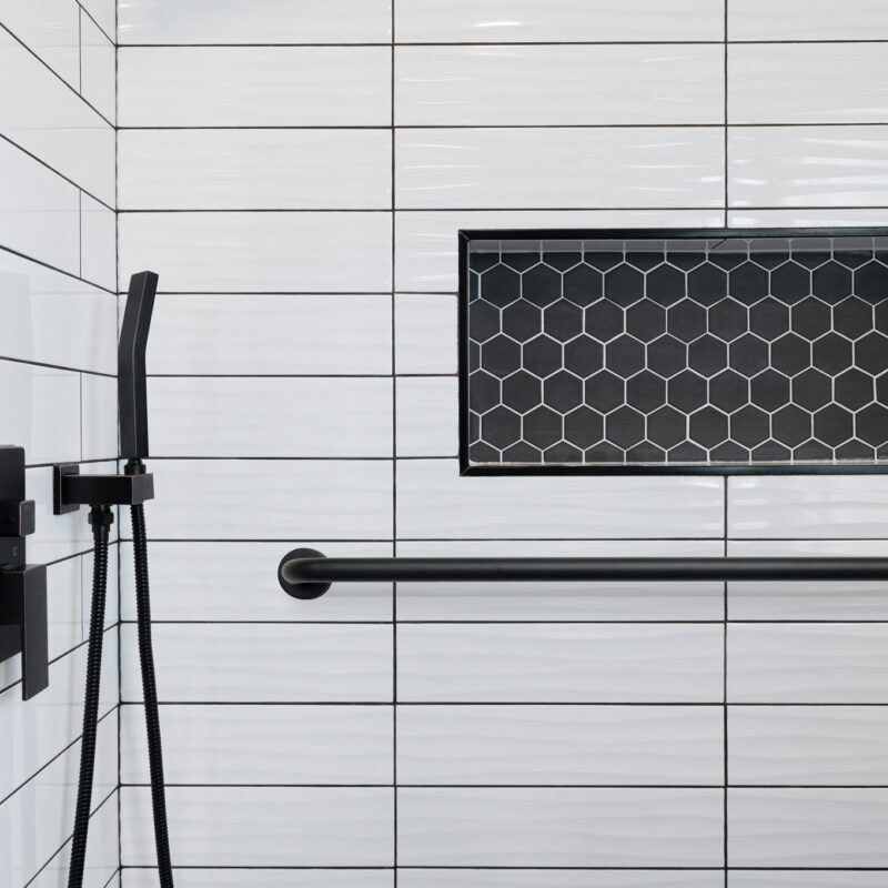 Detail of walk-in shower white subway tile, black hexagon tile i